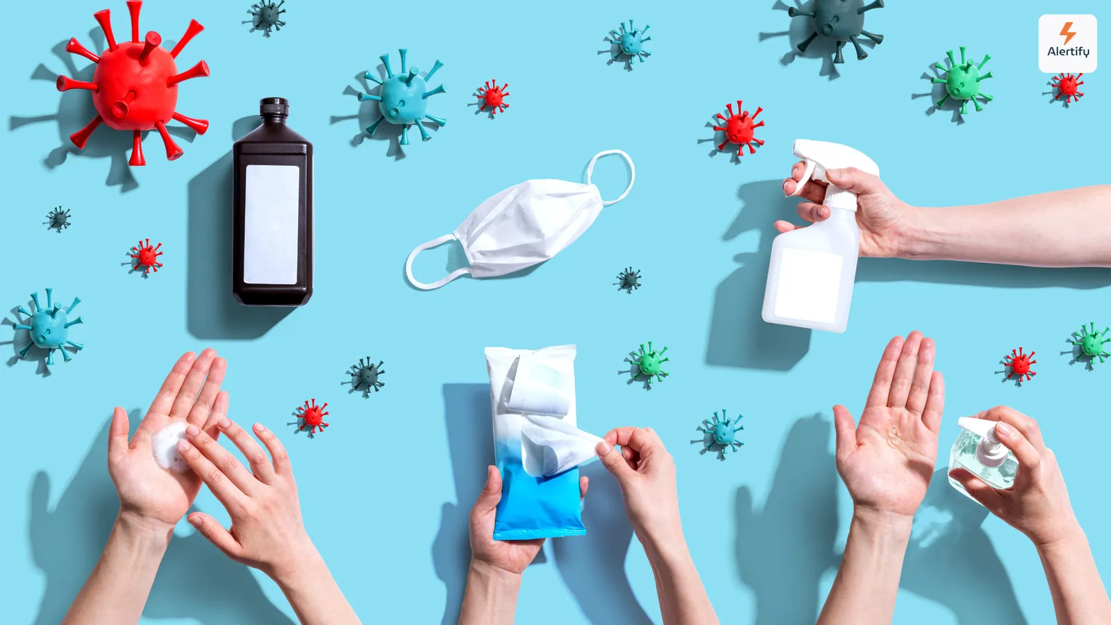 Flat lay of virus models, a face mask, sanitizer spray and hands using hygiene products
