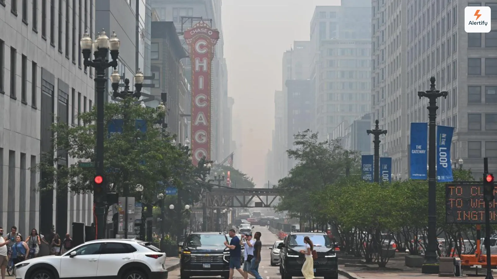 Wildfire haze swallowing the buildings down a Chicago street, with the Chicago Theatre sign lit in the foreground.