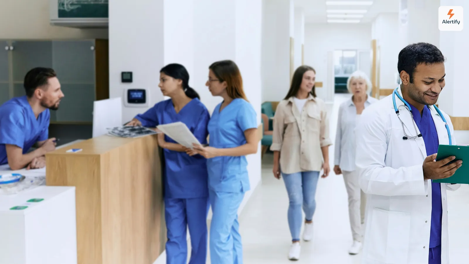 Clinicians and visitors walking past the reception desk in a bright hospital lobby