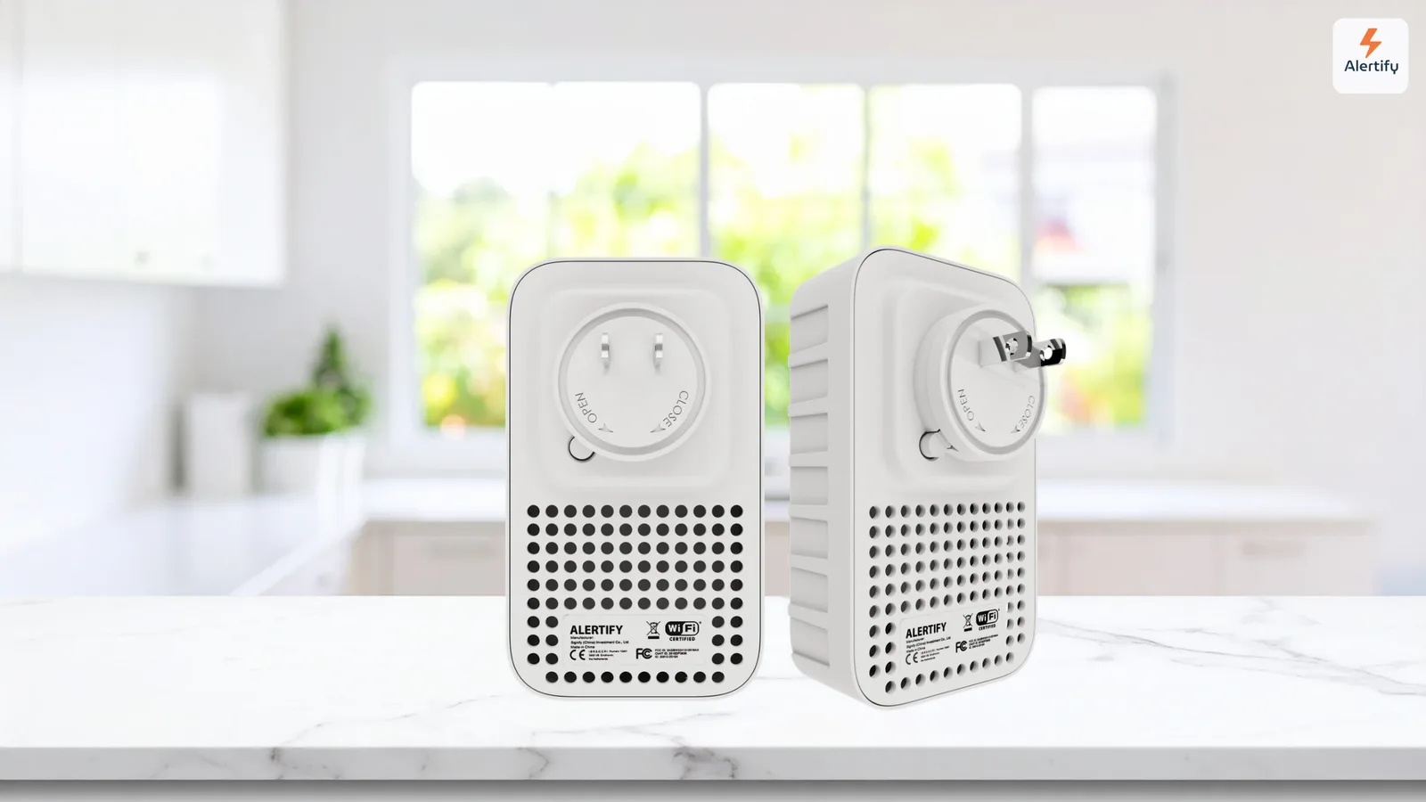 Two identical white Alertify plug-in monitoring devices, shown from the back at different angles, on a kitchen counter.